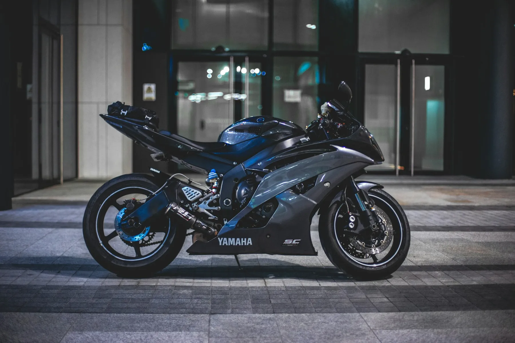 Moto deportiva azul aparcada de noche frente a un edificio