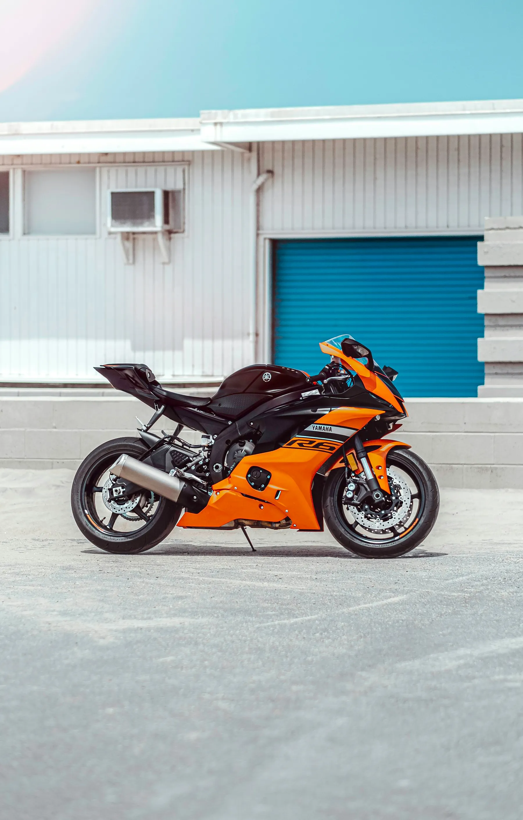 Moto deportiva naranja aparcada frente a una nave