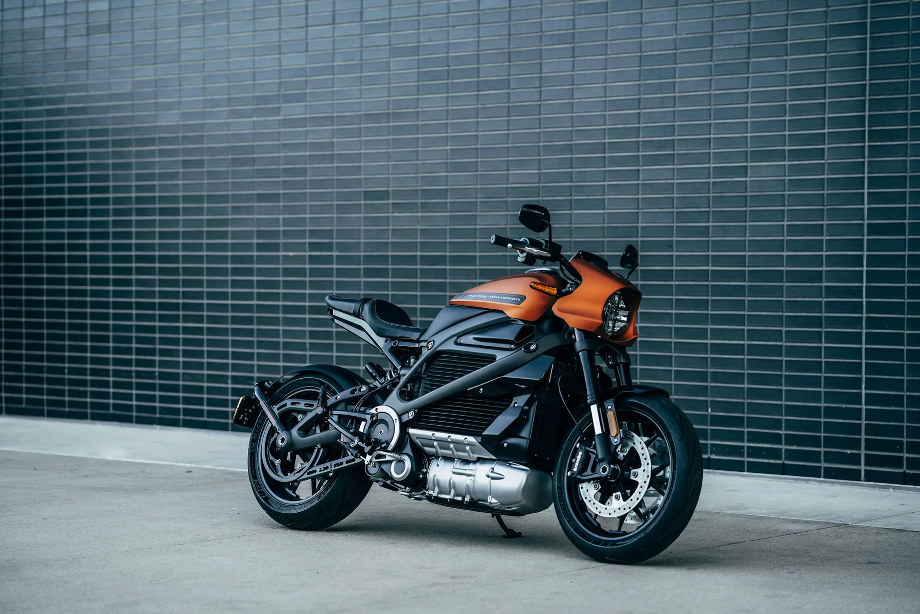 Moto naranja aparcada frente a una pared de azulejos