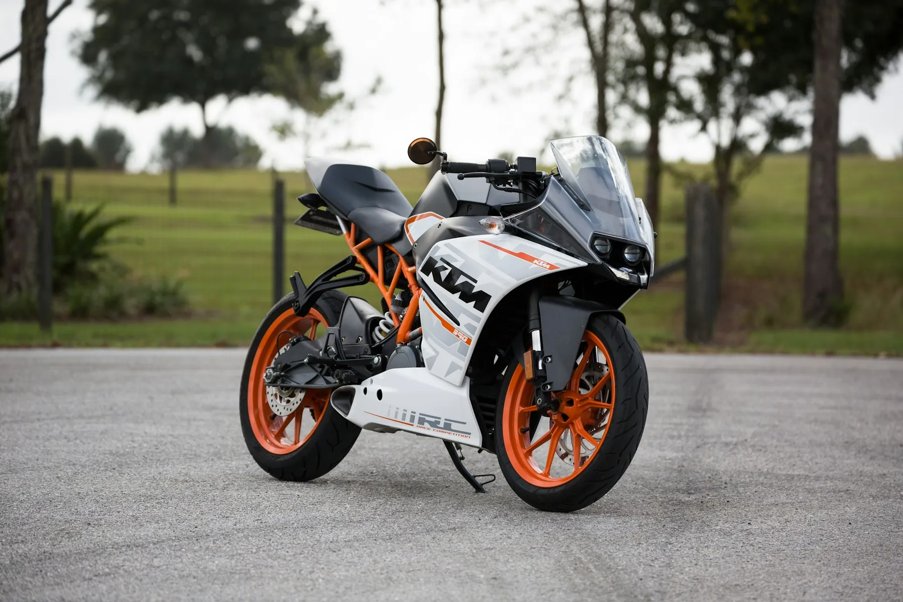 Moto deportiva blanca y naranja aparcada en un parque