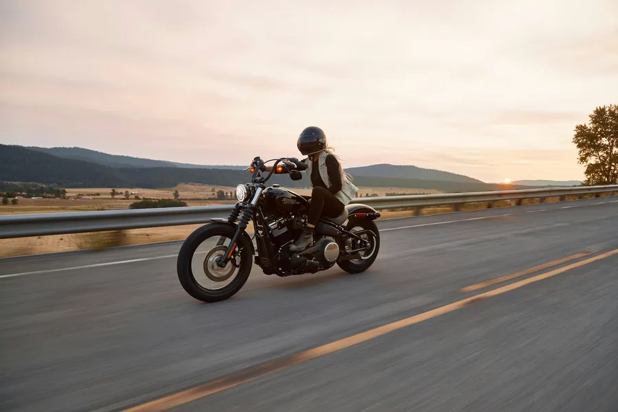 Motorista con casco integral circulando por una carretera al atardecer